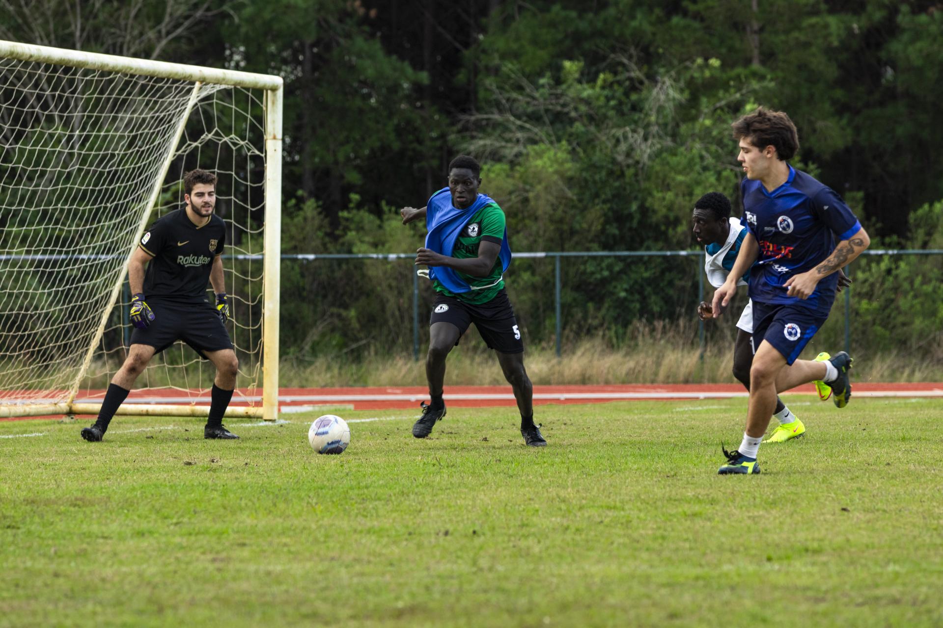 foto colorida horizontal de 3 homens jogando futebol em um campo