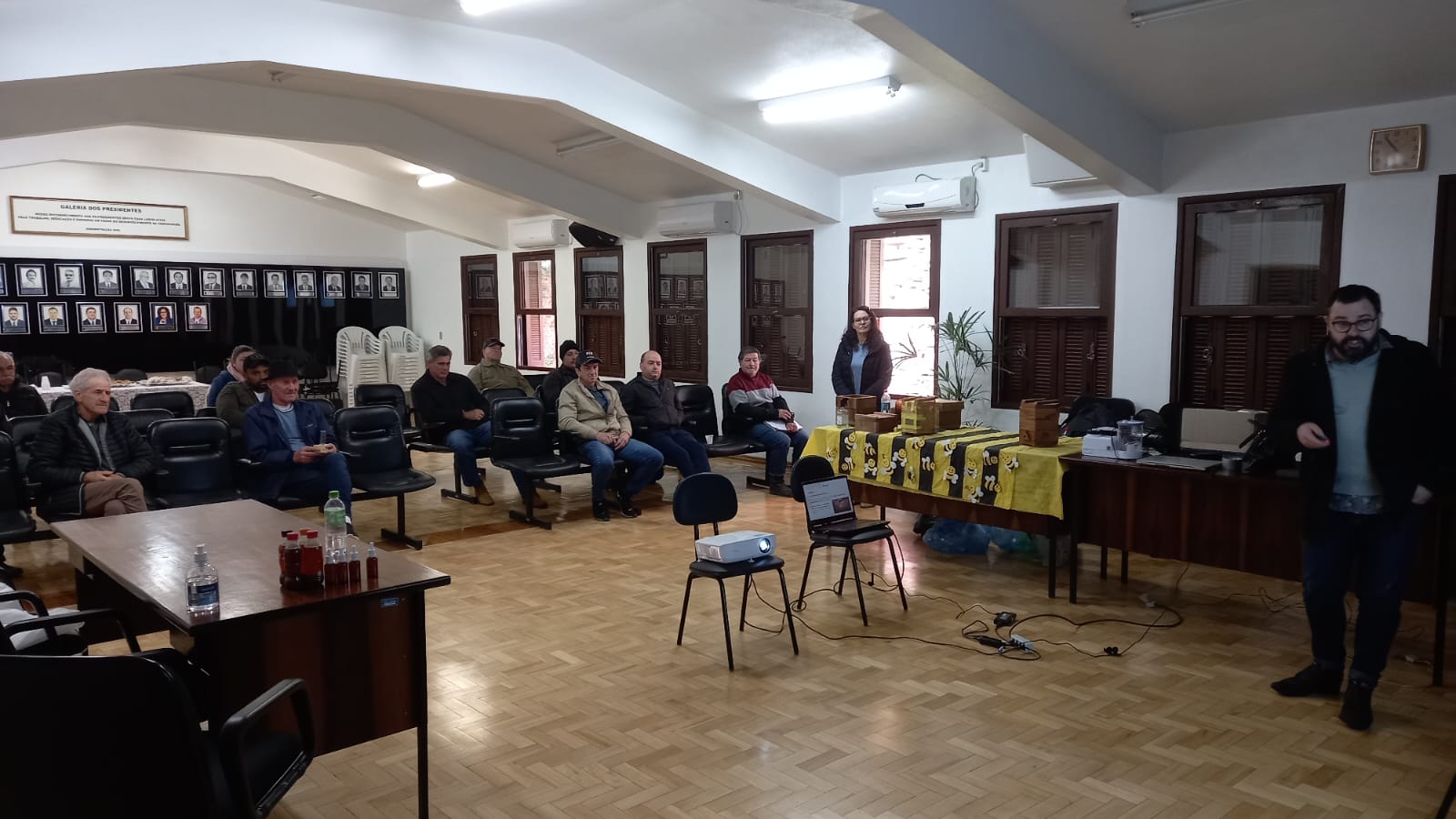 Foto colorida horizontal de grupo de pessoas sentadas em círculo em uma sala