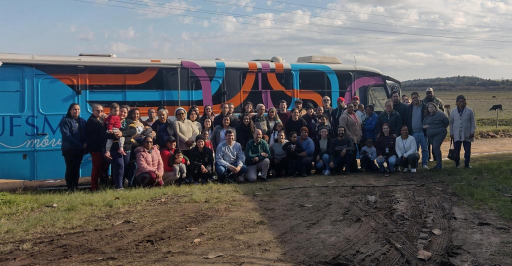 Foto colorida de equipe da UFSM e de membros da comunidade quilombola Rincão dos Martimianos na frente do UFSM Móvel