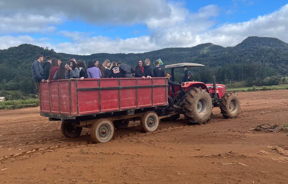 Foto colorida de equipe da UFSM em Dia de Campo em reboque puxado por trator