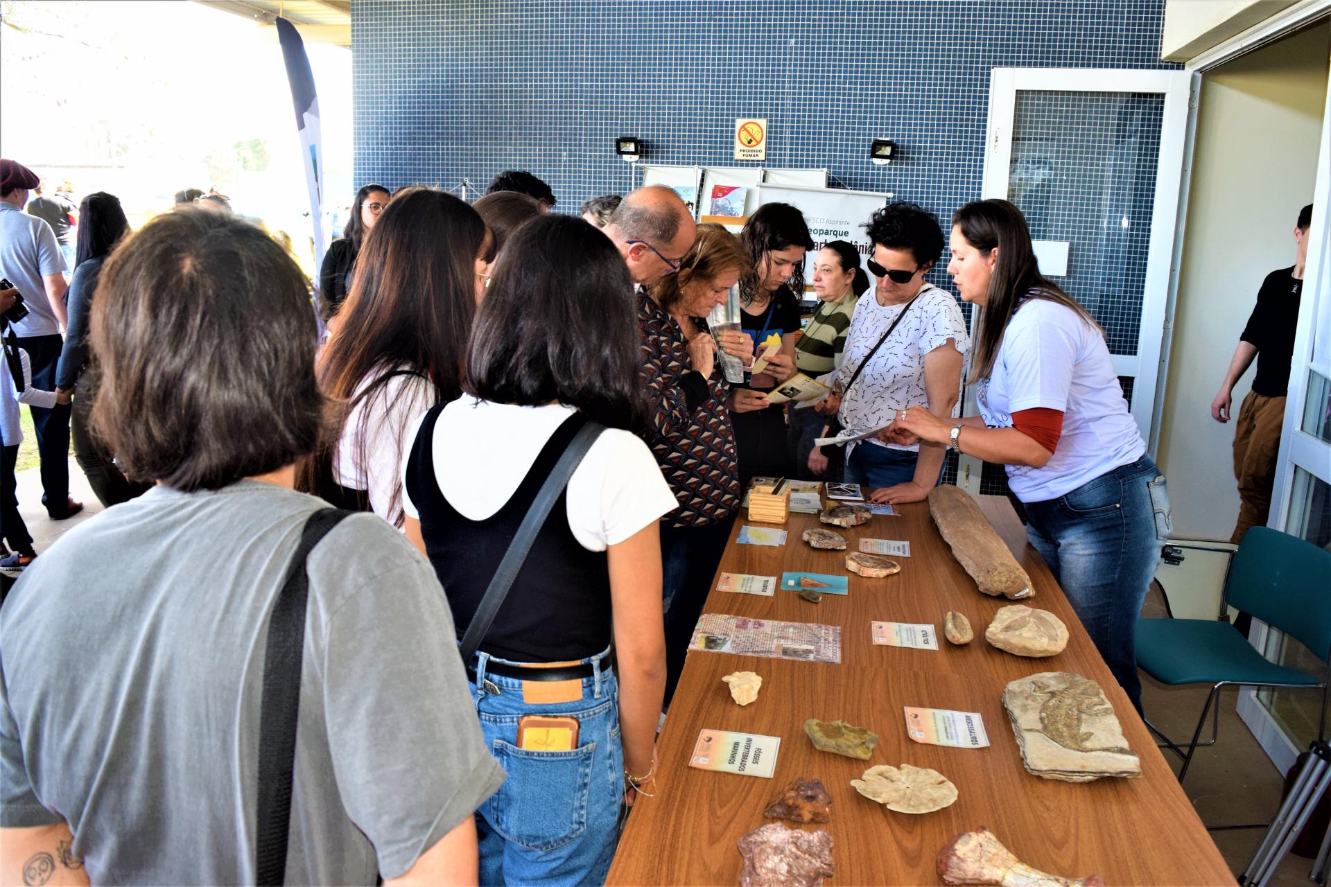 Foto colorida de pessoas visitando mesa com fósseis do CAPPA durante paleodia na UFSM