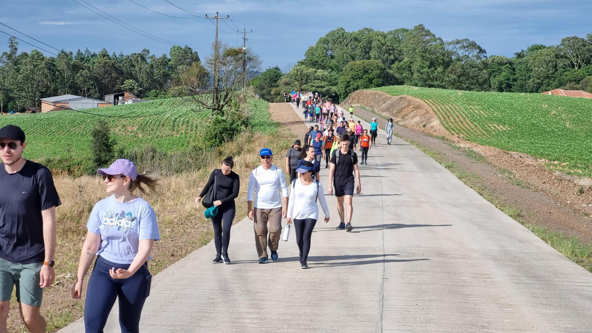 Foto colorida de pessoas caminhando em estrada rural de Silveira Martins