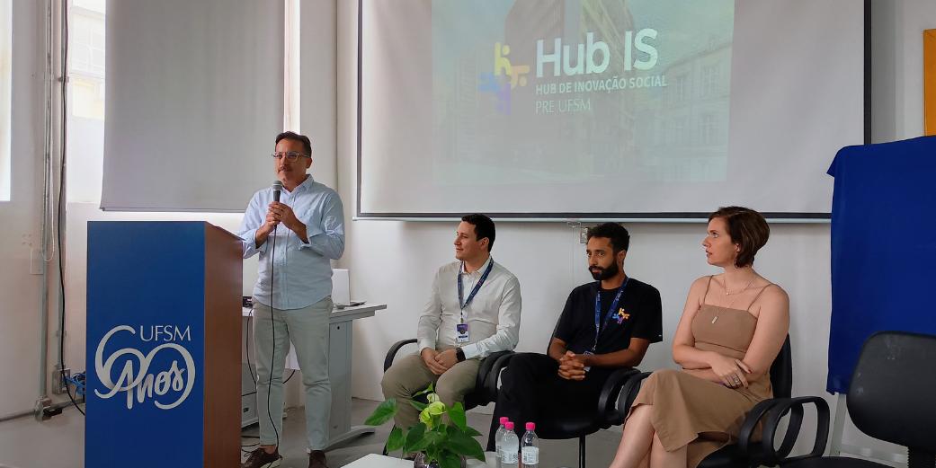 Foto colorida de inauguração do Hub IS com o Pró-Reitor Flavi Lisboa em pé, falando ao microfone