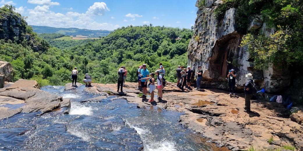 Foto colorida de pessoas na parte de cima de cachoeira em Nova Esperança do Sul