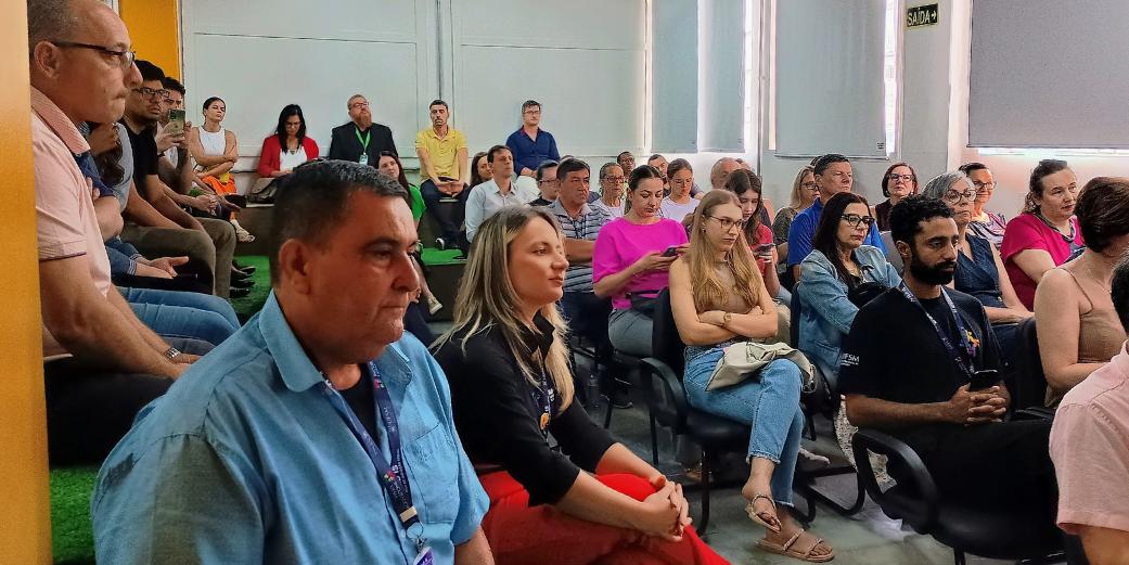 Foto colorida de pessoas sentadas em auditório do Hub IS