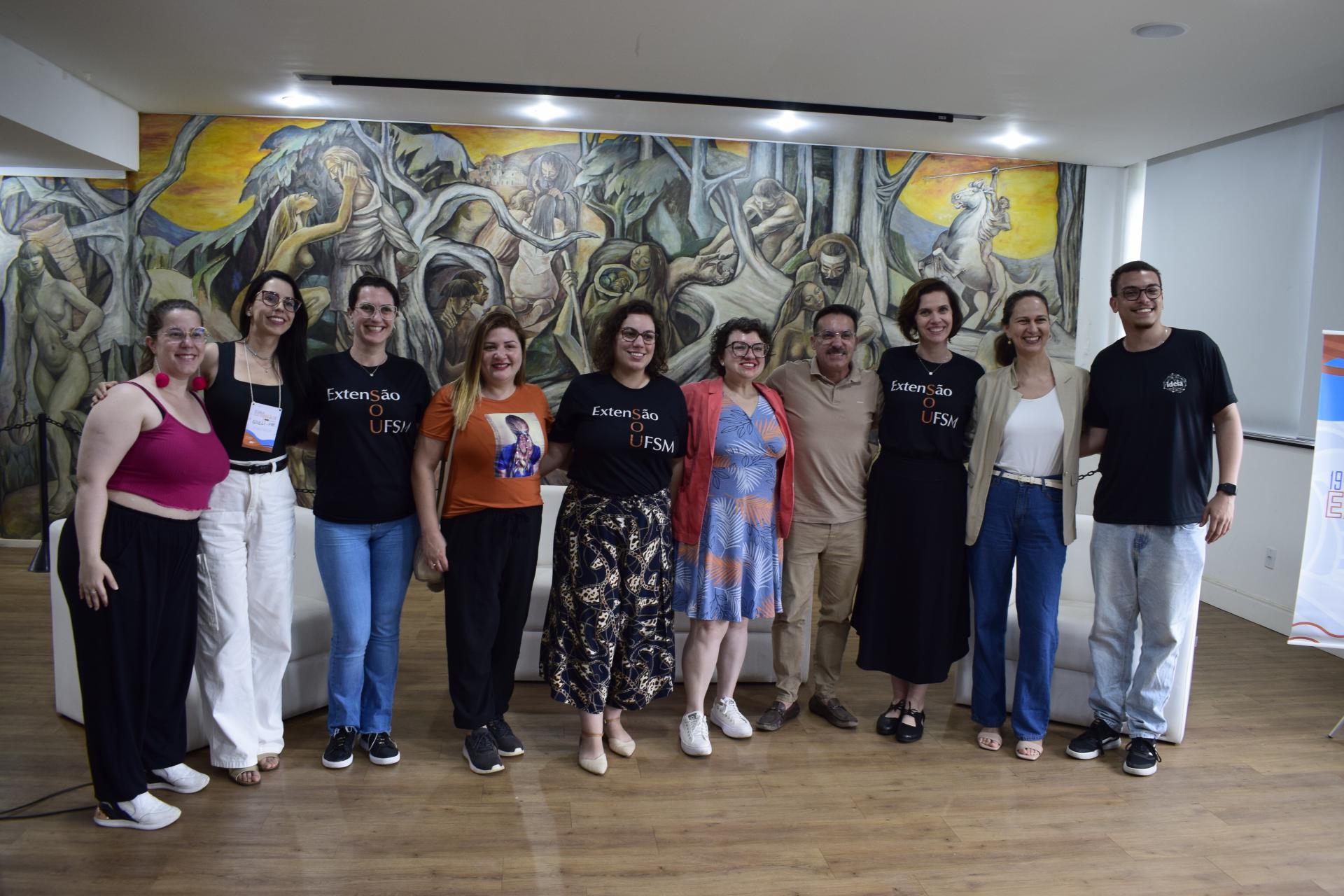 Foto colorida de participantes da mesa de popularização da ciência em pé, posando para a foto, no Salão Imembui