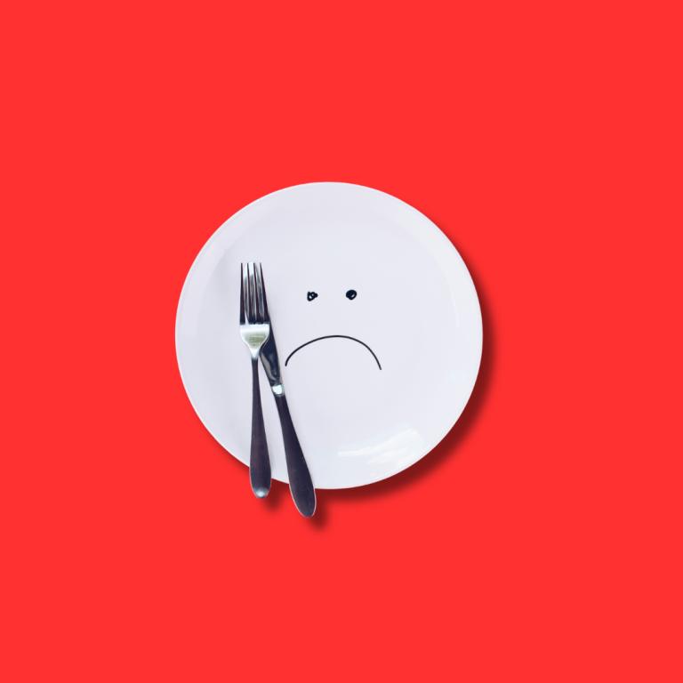 Uma imagem de fundo vermelho. No centro tem um prato de comida vazio, com um rosto triste desenhado.
