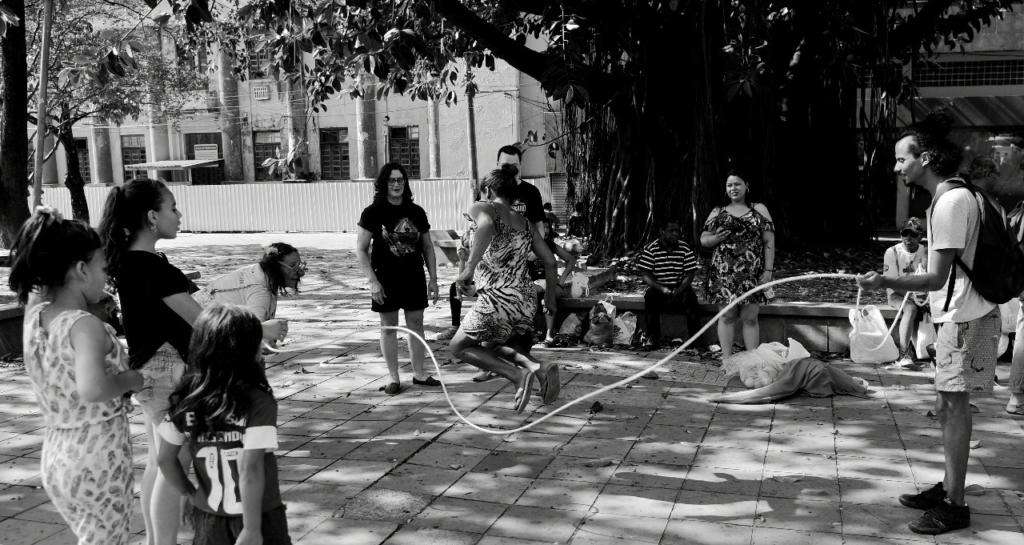 Foto preto e branca de pessoas pulando corda na praça