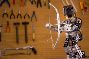 Um pequeno robô está de pé, segurando um arco e flecha.